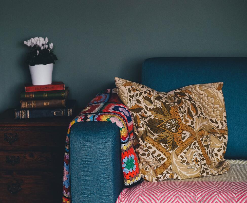 A patterned pillow sits on a blue sofa.