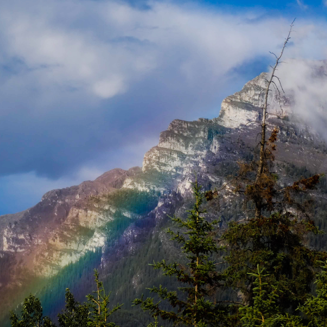 A rainbow appears over a mountain.